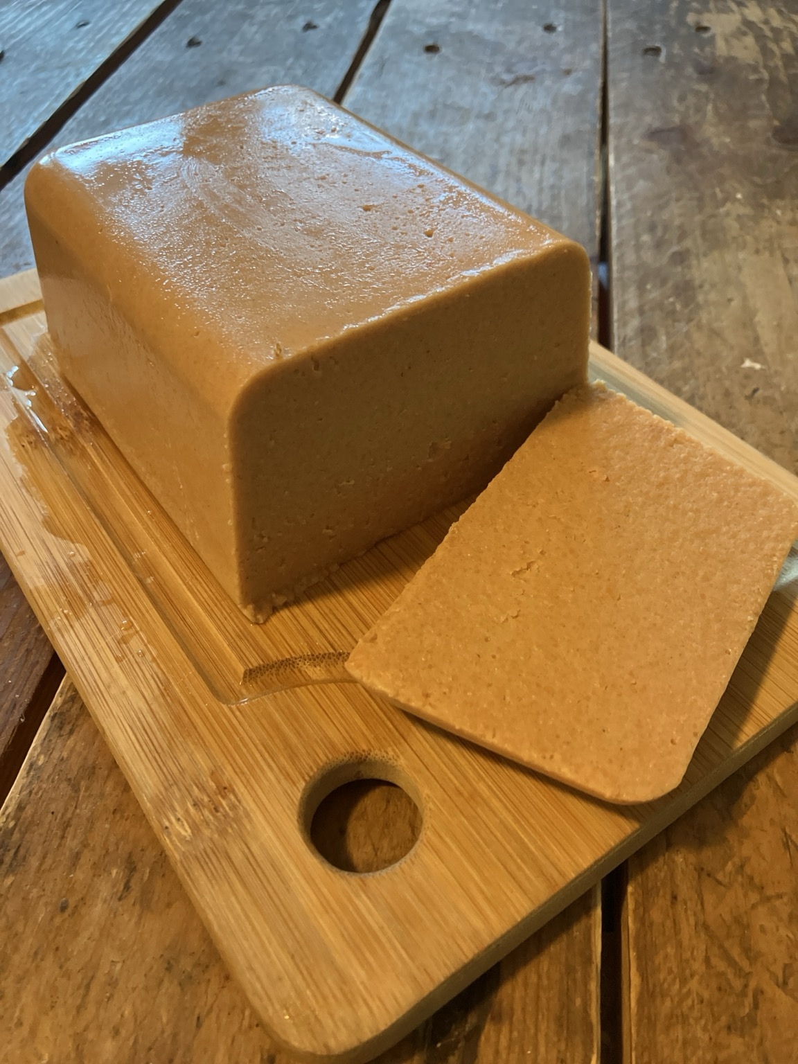 Bloc de tofu de lentilles corail maison sur une planche à découper , avec une tranche coupée