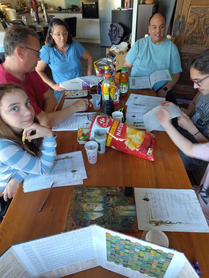 Table couverte de junk food , des feuilles de personnages et des joueurs autour.