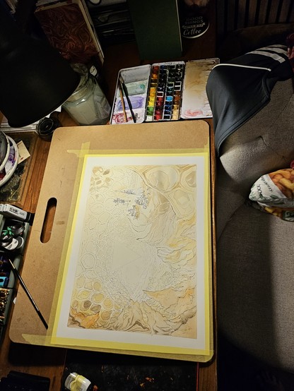 A large painting on a board, taking up most of a desk. The painting is very faint still, but shows an amber cave