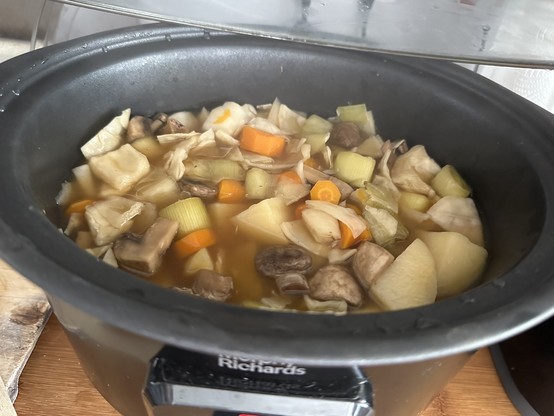 Slow cooker with the lid off exposing vegetables in a broth