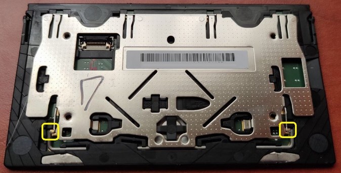 Photo of back side of a thinkpad touchpad. Two yellow rectangles highlight the retention clips that hold the stabilizer bar to the bracket.