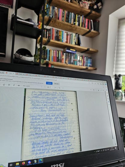 A laptop screen with a scan of a diary page on it. Above in the background you can see bookshelves with books on it.
