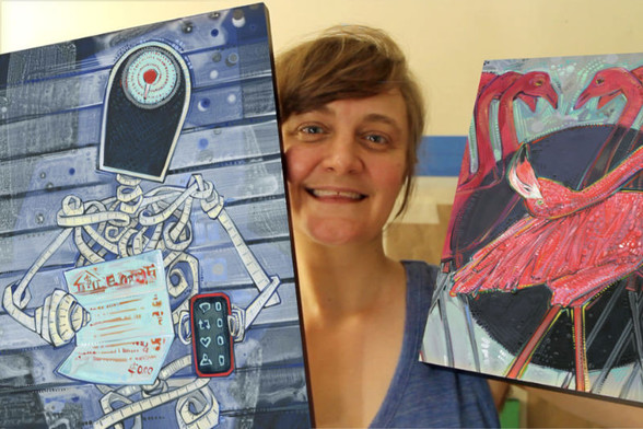 artist Gwenn Seemel holding two paintings: a skeleton made of measuring tape and a flamingo that's bending over backwards