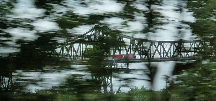 Ett tåg som susar fram på en bro att från vårat tåg. 