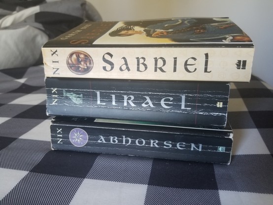 Photo of the 3 books stacked on top of each other, showing the minimal but beautiful art on the spines, with symbols relevant to the books on them.