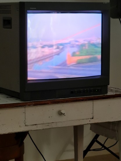 Foto eines alten, russischen Monitors auf einem alten, weiss lakierten Holztisch. Es wird der Film 'In the Womb of a Civil Woman' von Viktor Korochka gezeigt.