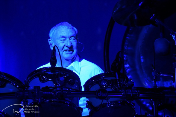 Former drummer of Pink Floyd, now on tour with his own band, laughing behind his drum kit in blue light.