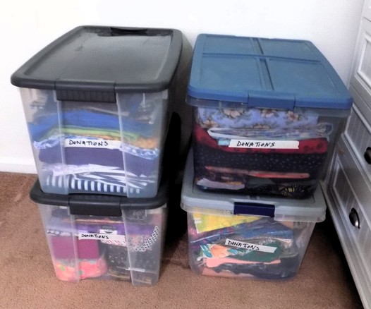 Four large bins marked DONATIONS that are packed with all colors of fabric yardage, precuts and useable scraps from my stash.