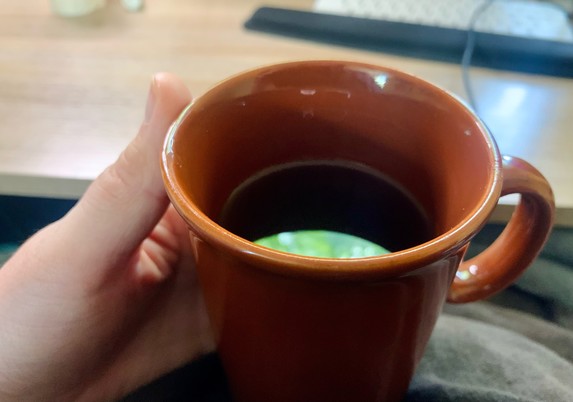 My hand is cupping a burnt sienna colored mug on my lap. A sliver of bright green out my window reflects in the surface of the dark tea.