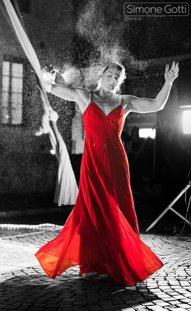 A woman in a red dress spraying herself with perfume.