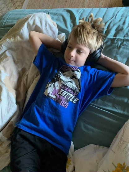 Finn, Seren's younger brother, relaxes on a mattress with over the ear  headphones on.