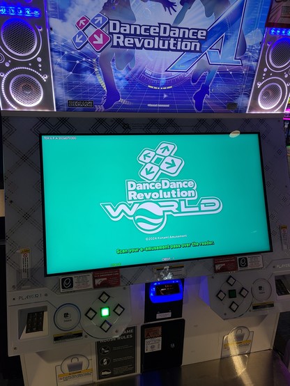 Photo of a dance dance revolution A arcade cabinet, showing the DDR World title screen. 