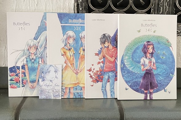 Photo of four volumes of the comic arranged next to each other. The covers show various characters. 
