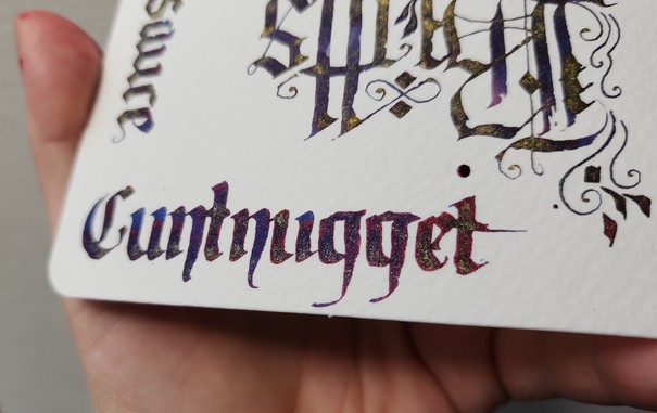 Close up on the word 'Cuntnugget' showing the gold shimmer and red sheen in the ink.