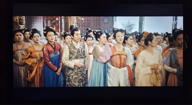A crowd of young women and a few men in colourfull Tang era clothes.