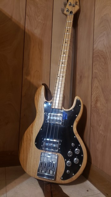 A natural finish Peavey T-40 propped up in the corner of the spare bedroom in my house, the walls of which are paneled with wood that looks amusingly similar to the grain of the bass.