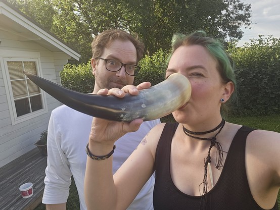 Jen in the foreground, drinking from a large drinking horn - her friend right behind looking at the camera in a meaningful way