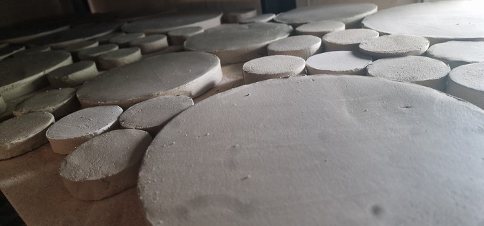 Round tiles packed on shelves for drying. 