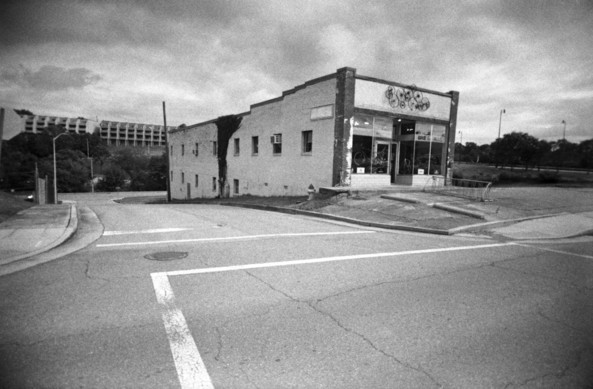 Black and white photo of a somewhat rundown building in the midst of a paved area. The wide angle of the plastic lens exaggerates the feeling of isolation.

It's the home of a bicycle shop in Maryville, Tennessee.