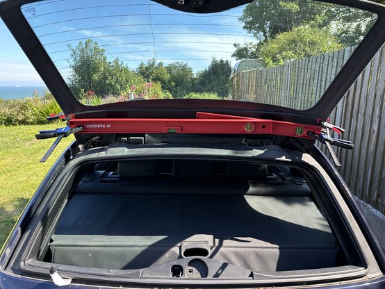Rear glass window of a car raises up. Across the bottom of the window are some spirit levels which are clamped at either end to the window