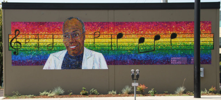 mural showing a black man in a white coat in front of a rainbow of sheet music for Somewhere Over the Rainbow