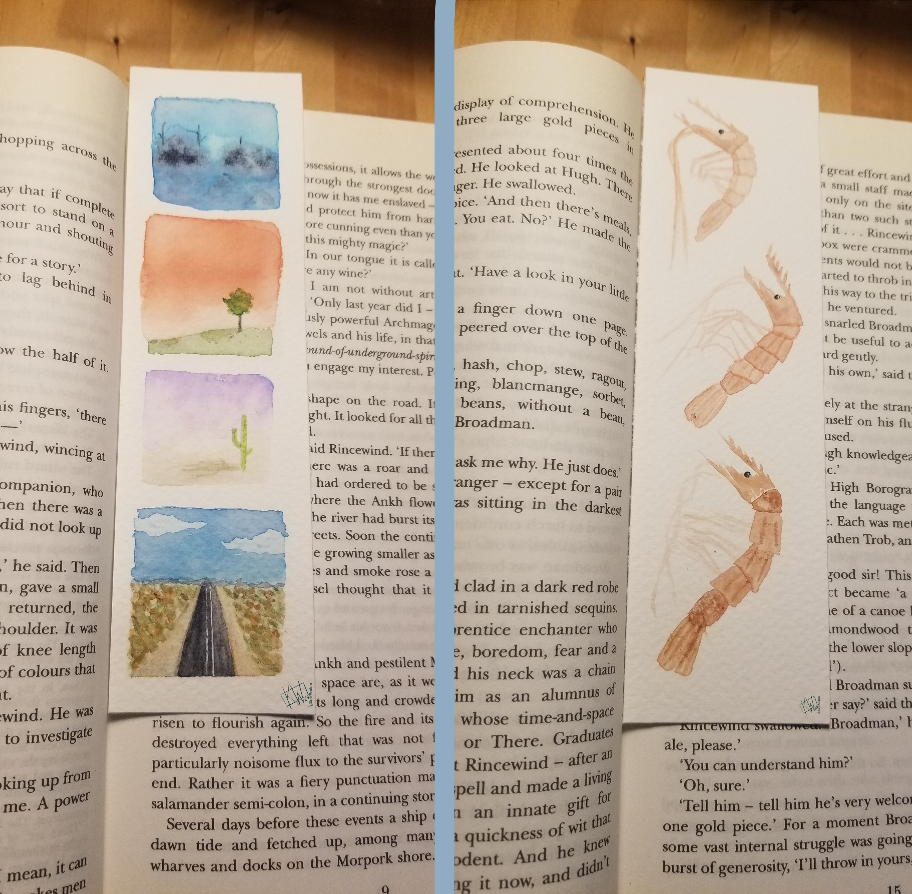 Side by side photos of 2 books lying open with bookmarks. Left bookmark is decorated with a column of landscapes- foggy, sunrise, sunset, & a highway reaching off toward distant mountains. Right bookmark is decorated with many shrimp.