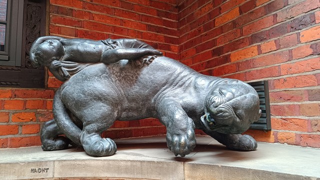 Another sculpture of a baby reclining on the back of a big cat, but this cat doesn't look any happy at all.