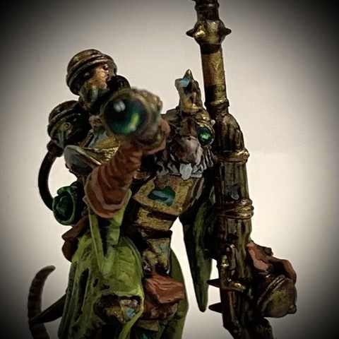 Close-up of a Skaven rat-man. He has a telescope looking at the camera, his head behind it. He carries a long rifle and wears green-yellow robes and tarnished bronze armor. 