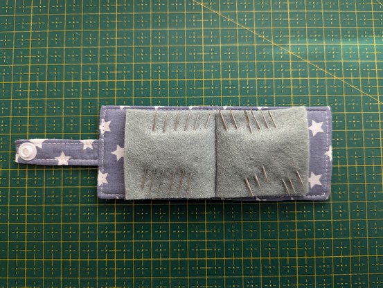 Inside of the needle book. Grey felt is used here to make the 'pages'. Several handsewing needles are pinned through the pages.