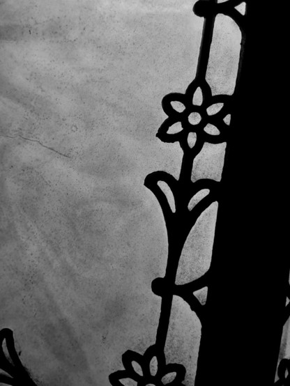 Metal cutouts on a stained glass (sheet) lampshade. Black and white.