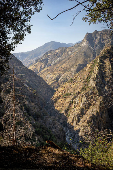 A stunning view of rugged mountains and valleys in King's Canyon National Park, California, captured during a scenic drive. The arid landscape and vast wilderness create a breathtaking scene. 