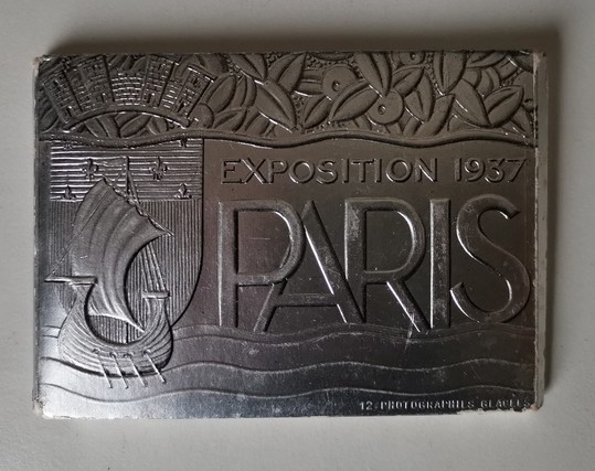 Porte-cartes en carton argenté et gaufré.
Exposition 1937
Paris.
Logo de la ville de Paris avec le navire, les flots et le blason.
Un feuillage caractéristique de l'art déco couronne le tout.