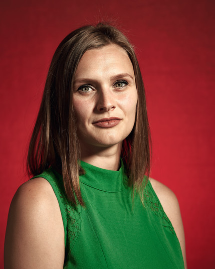 woman in a green top against a red background.