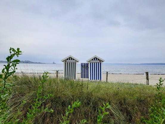 3 gestreifte Umkleidehäuschen am Strand.