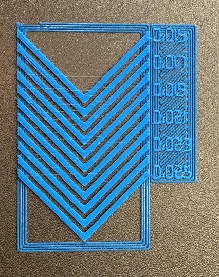 3D print consisting of chevrons with numbers next to them, that run from 0.15 to 0.025 in 0.001 steps