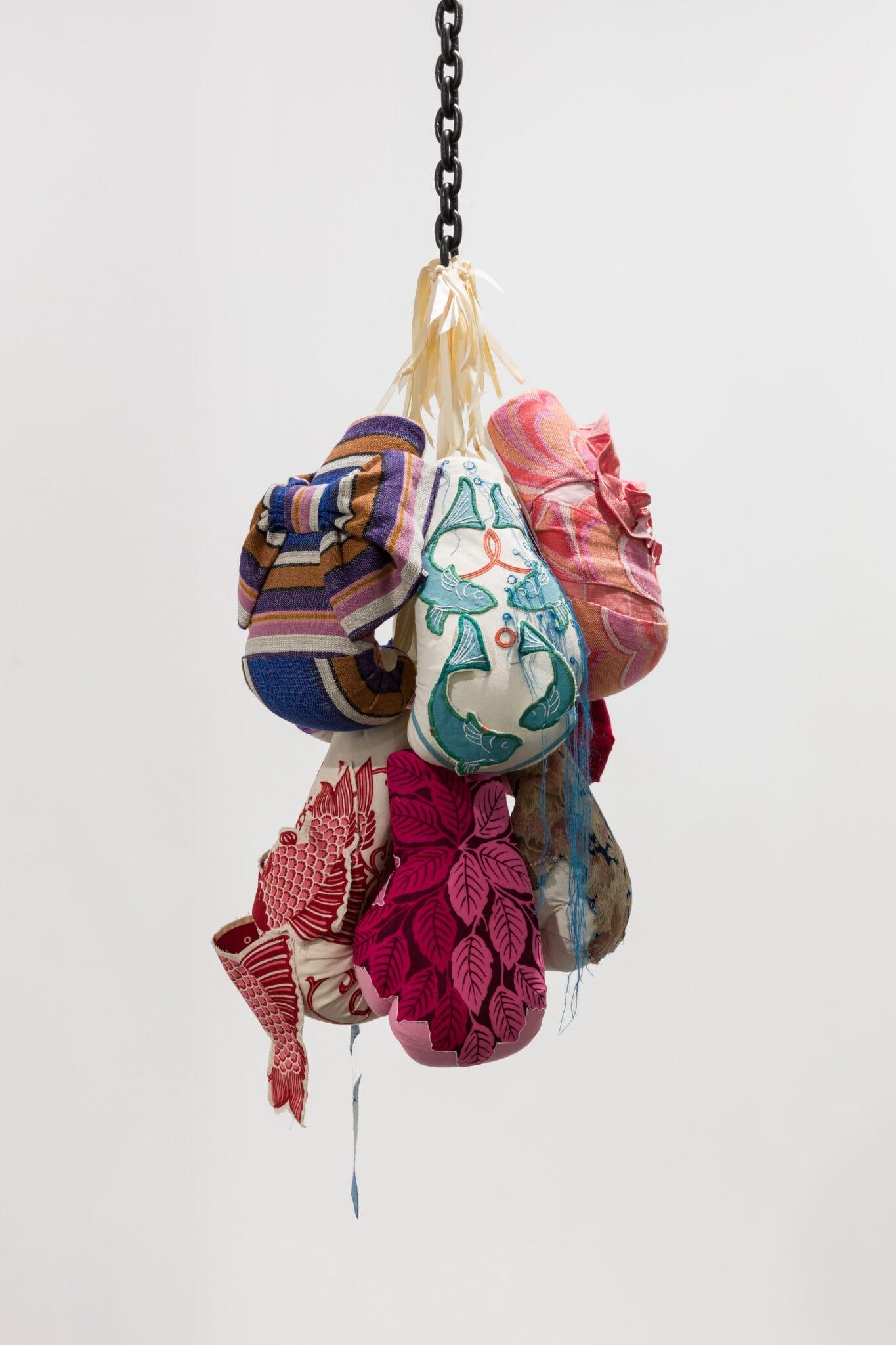 a collection of boxing gloves covered in patterned fabric suspended from a chain