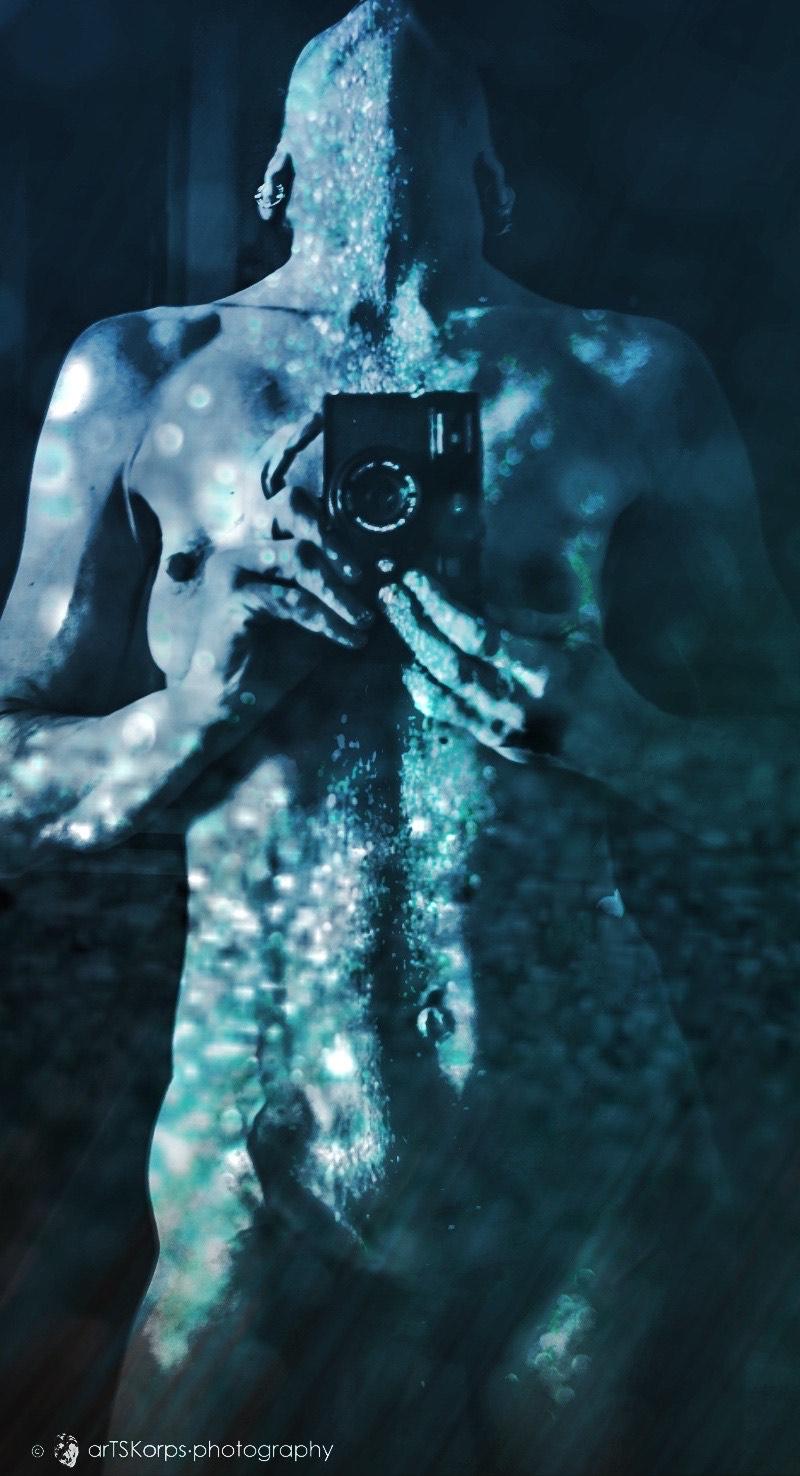 Colour photo in blueish green colours, double exposure, portrait format of a female torso, taking a photo of herself into a mirror, camera between her bare breasts. Doible exposed with small glittering pieces of a broken car window shield. Impression as if being under water or covered with drops of water Colour photo in blueish green colours, double exposure, portrait format of a female torso, taking a photo of herself into a mirror, camera between her bare breasts. Doible exposed with small glittering pieces of a broken car window shield. Impression as if being under water or covered with drops of water