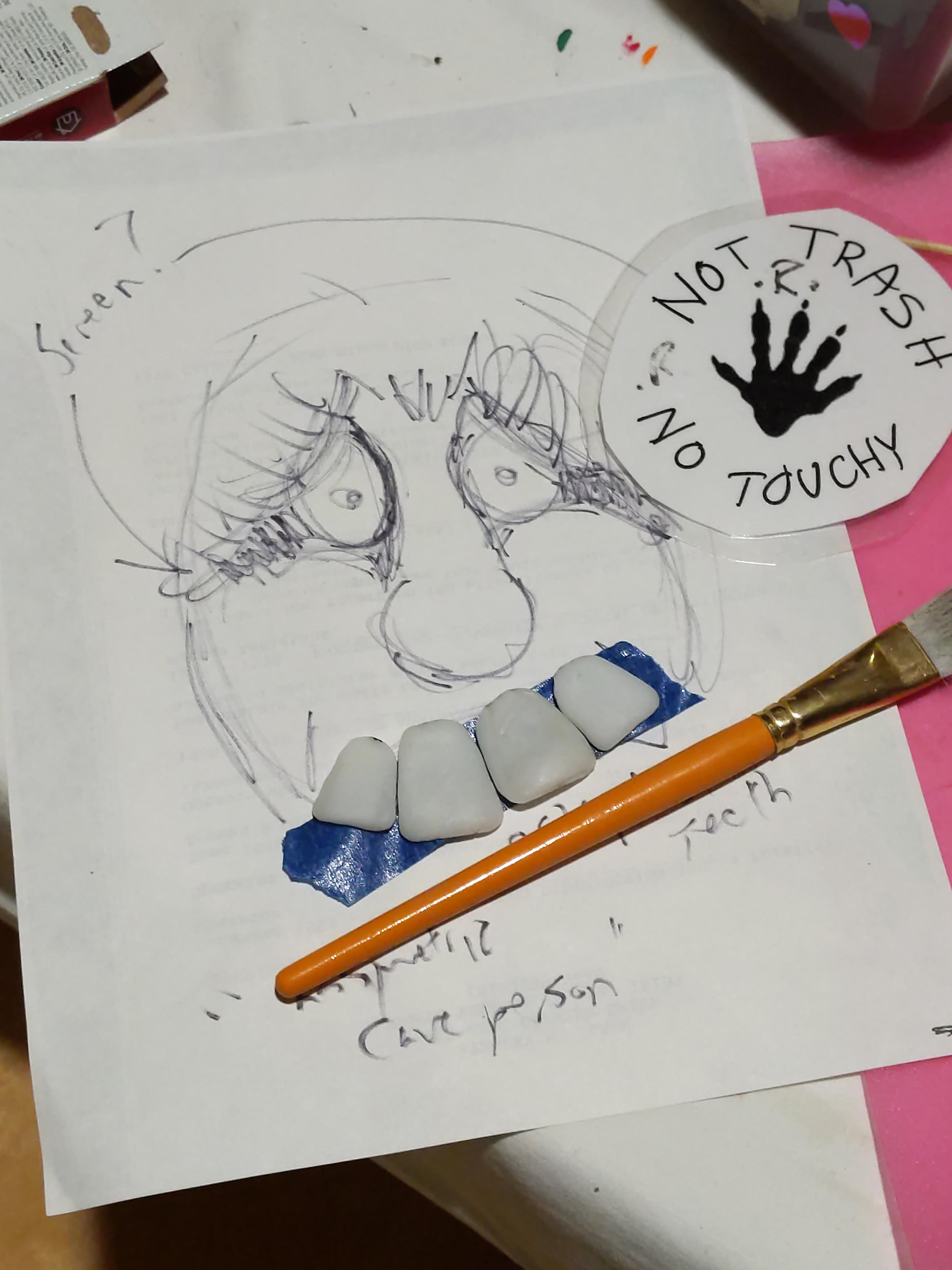The teeth, sculpted from thermoplastic, positioned on a piece of tape over the sketch.
A "not trash, no touchy" sign can be seen in the background.