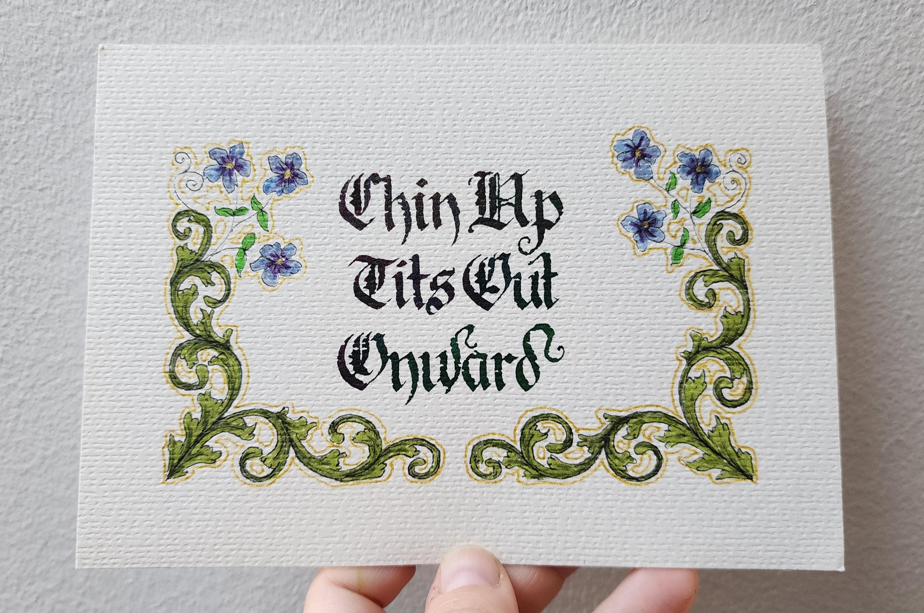 'Chin Up, Tits Out, Onward' calligraphed in fancy blackletter script in blue-green ink and decorated with a border of swirling vines that curl up from the bottom along the sides and sprout purple-blue flowers at the top