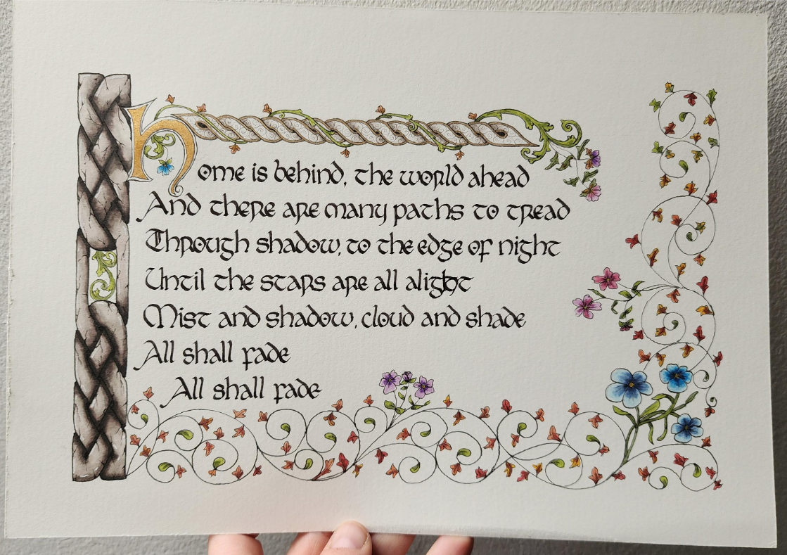 Black ink calligraphy surrounded by a decorative border of swirling leaves and knotwork.
Calligraphed in insular script;
'Home is behind, the world ahead
and there are many paths to tread
Through shadow, to the edge of night
Until the stars are all alight
Mist and shadow, cloud and shade
All shall fade
All shall fade'
The first 'h' is big and painted gold.
There's a bar of Celtic knotwork down the left coloured to look like cracked stone, with a gap in the middle with vines showing through. There's another narrower border of knotwork cross the top, with vines curling around it, and then loose curling vines with leaves and flowers across the bottom and right.
