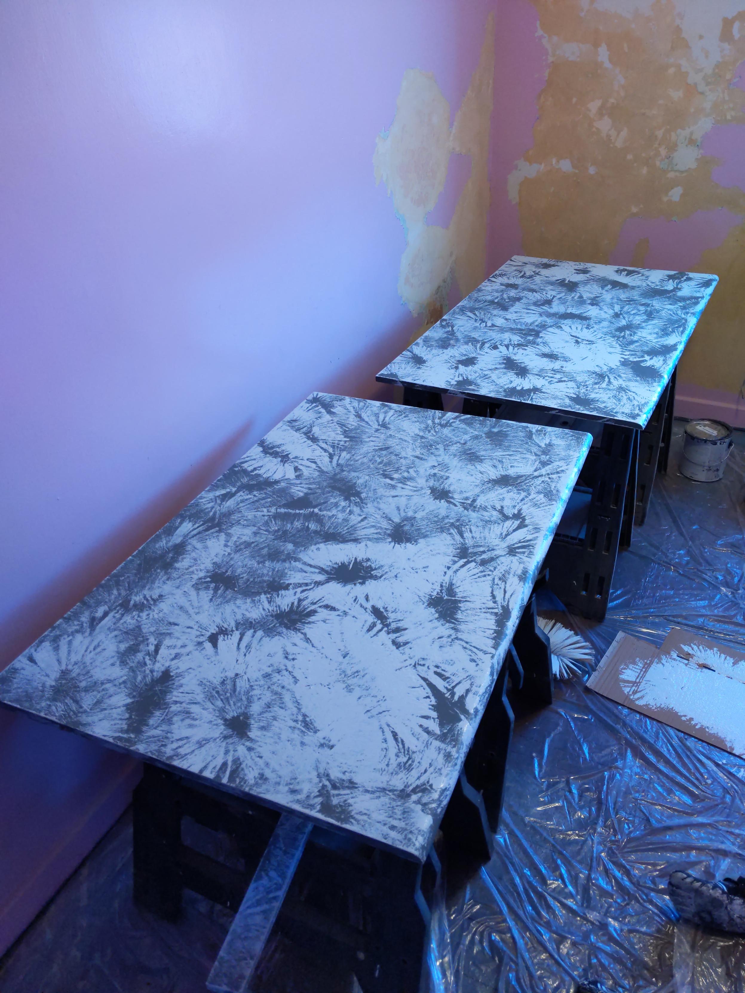 Pieces of reclaimed wood. They have been sanded, patched, and now painted for use as a bench top.
The top is dark gray, with a lighter gray splatter pattern over it. The paints are the same color as the walls, and the visual texture was applied with the brush used to texture the ceiling.