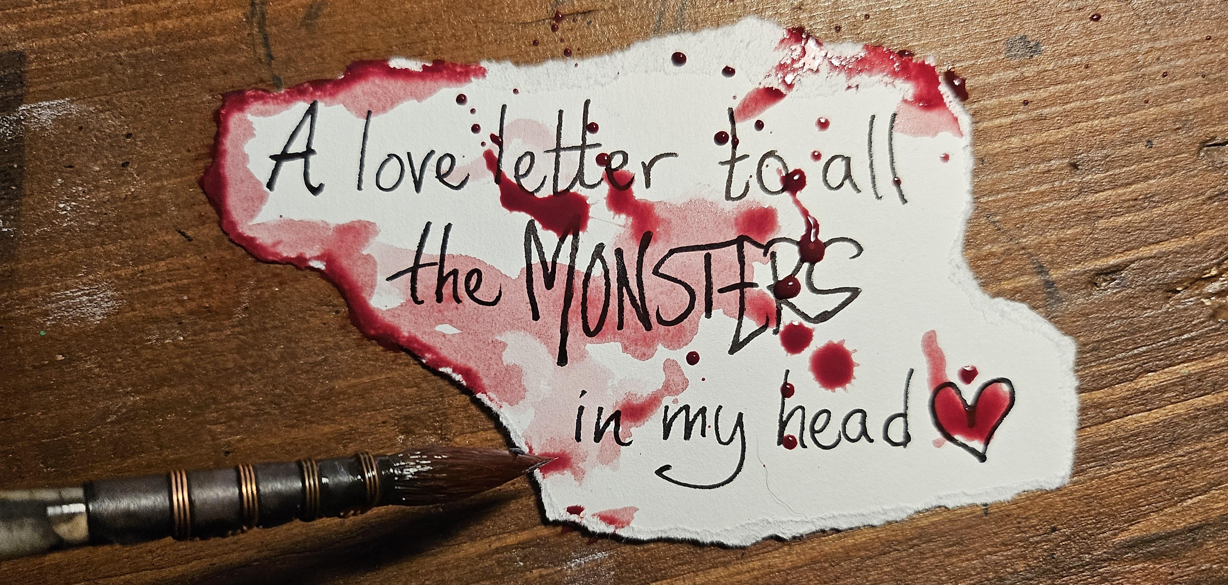 Hand written text on a torn piece of paper: "a love letter go all the MONSTERS in my head". The paper is scattered with red watercolour. It simulates jam. Yes.