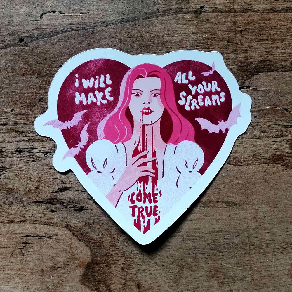 Photo of a heart shaped sticker featuring a pink haired vampiree with blood dripping from her mouth with the text "I will make all your screams come trrue"