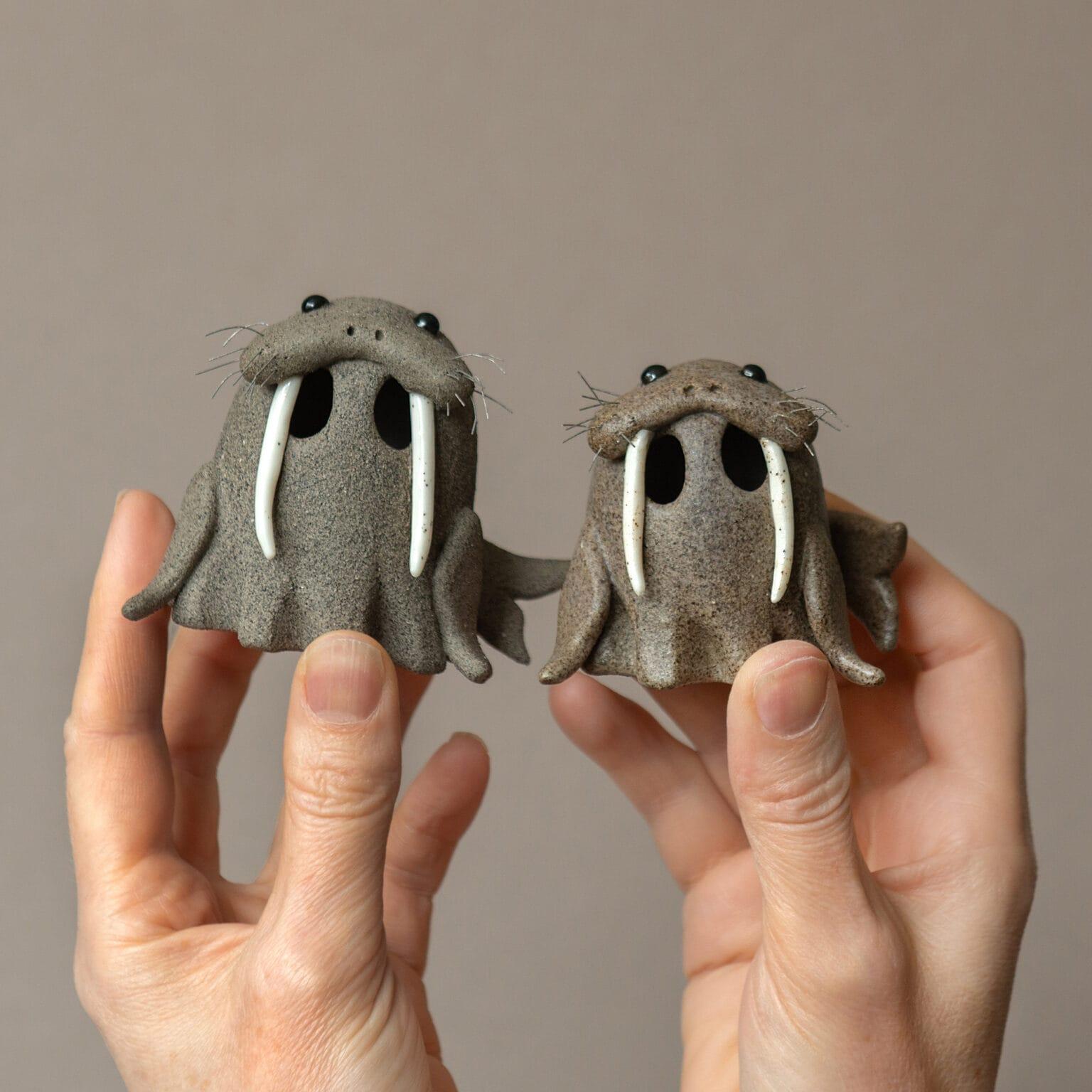 2 small ceramic ghosts posing as walruses with large tusks