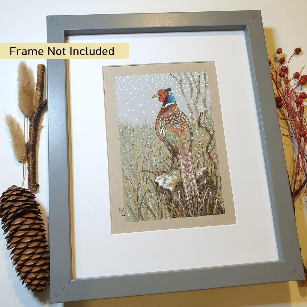 A small colour drawing of a pheasant in wintertime, with a grey sky and snow falling on a rural scene.
Pheasants are large, long-tailed game birds. The males have rich chestnut, golden-brown and black markings on their bodies and tails, with a dark green head and red face wattling.
An original art work, please note that the frame is not included.
Colour pencil and mixed media on acid free toned artist paper
5 by 7 inches (12.7 by 17.8 cm).