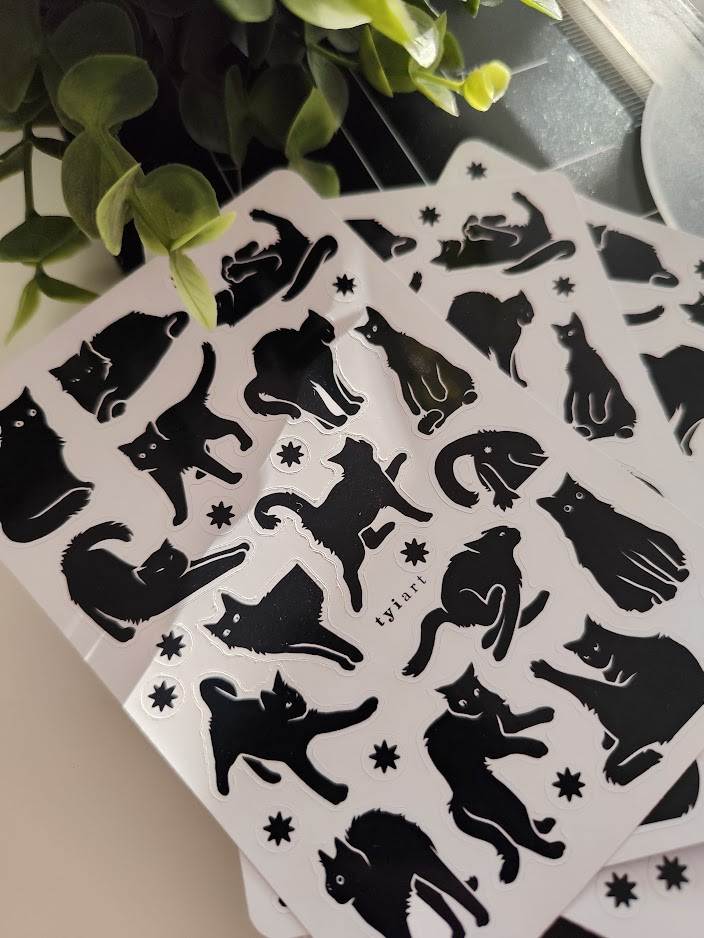 photo of a pile of black and white sticker sheets with silly black cats on them