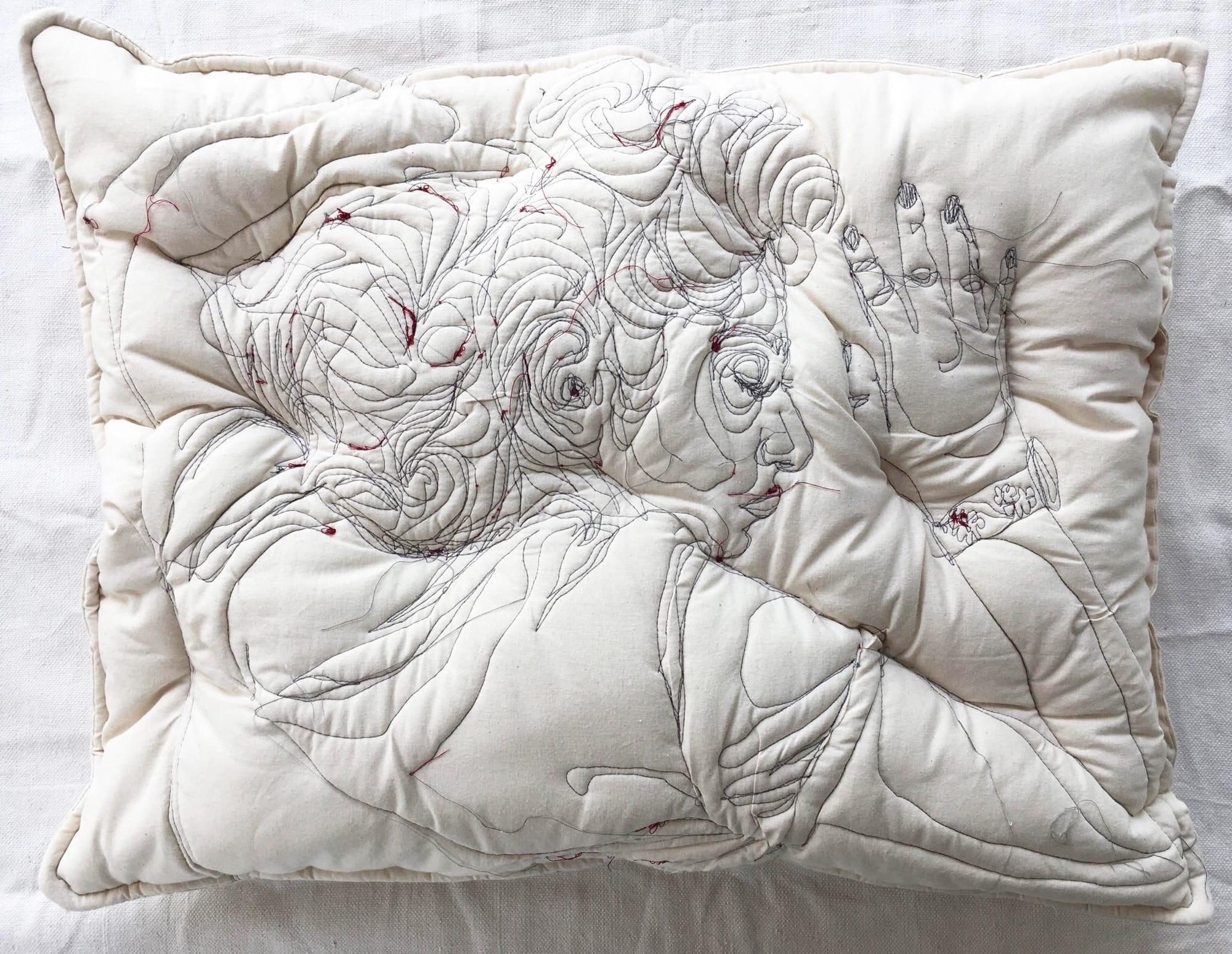 a white pillow with a sleeping woman stitched onto it