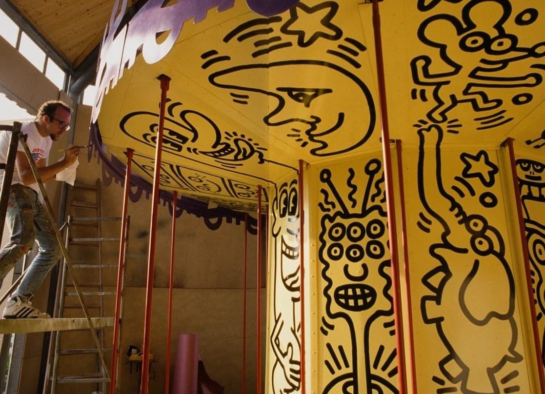 keith haring paints a vibrant yellow carousel with black figures