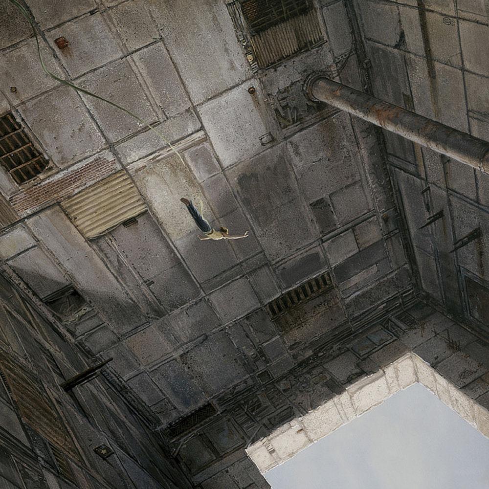A disconcerting angled view down as a woman dives through a massive chamber toward a square opening below. The walls of the chamber are mix of odd shaped rectangular concrete panels with rusted greats, boards and bricks breaking up the monotony of the facade. An elastic line trails the diver loosely as she spreads her arms out wide carried downward by gravity. Her feet are together and her back arcs slightly in perfect form as she shoots through the space toward the light below.