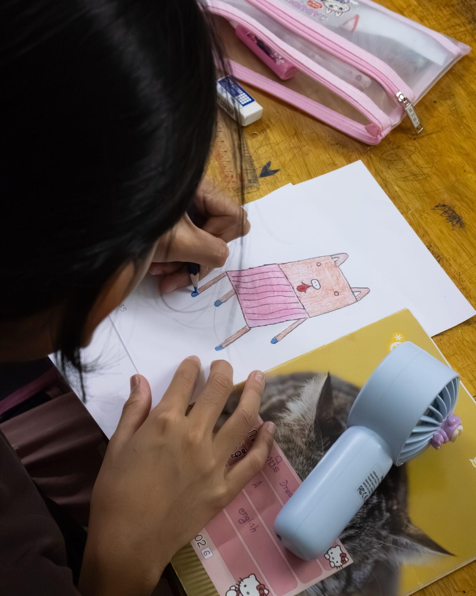 a child draws a whimsical chair design with colored pencils